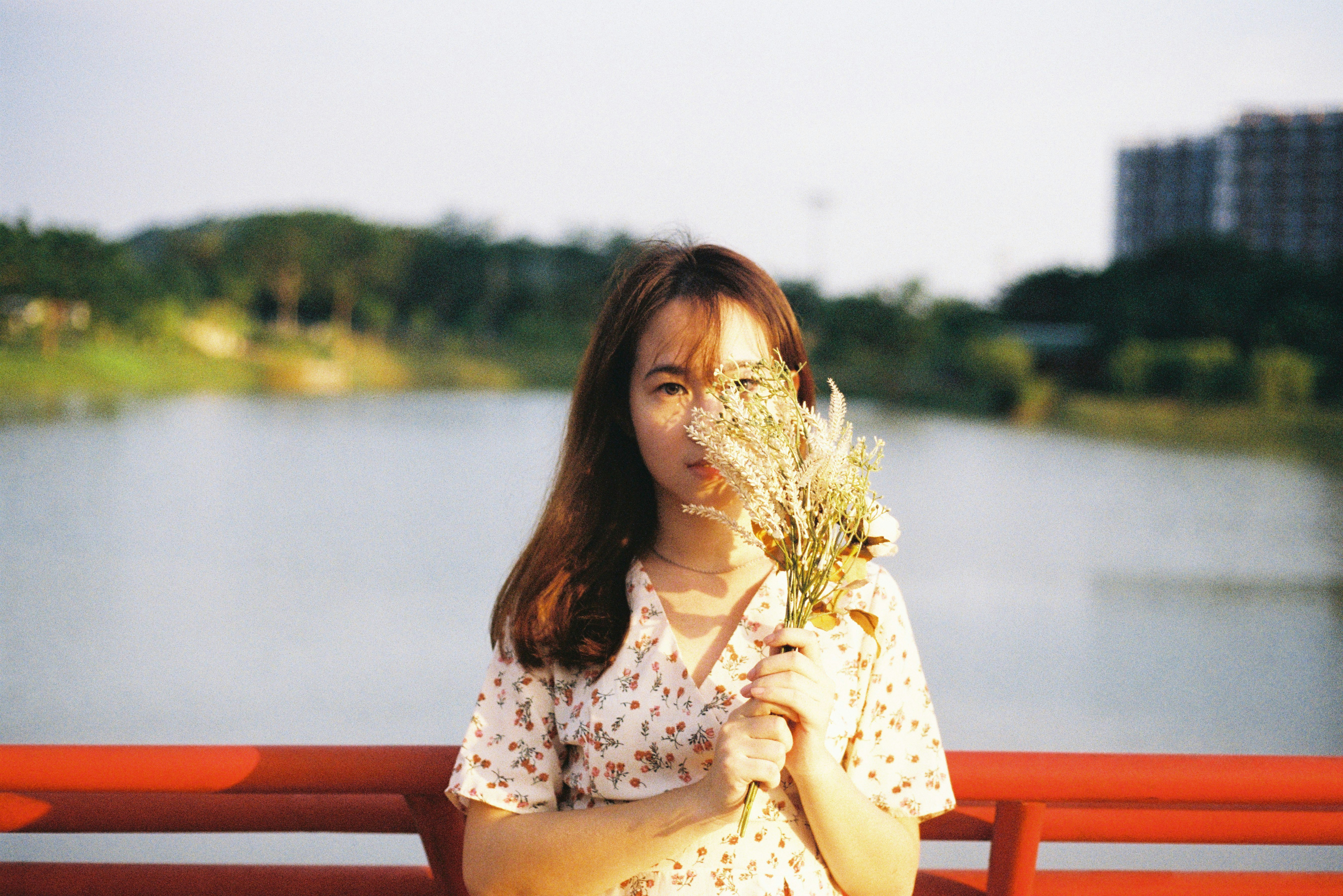 woman in white and red floral dress sitting on red wooden bench